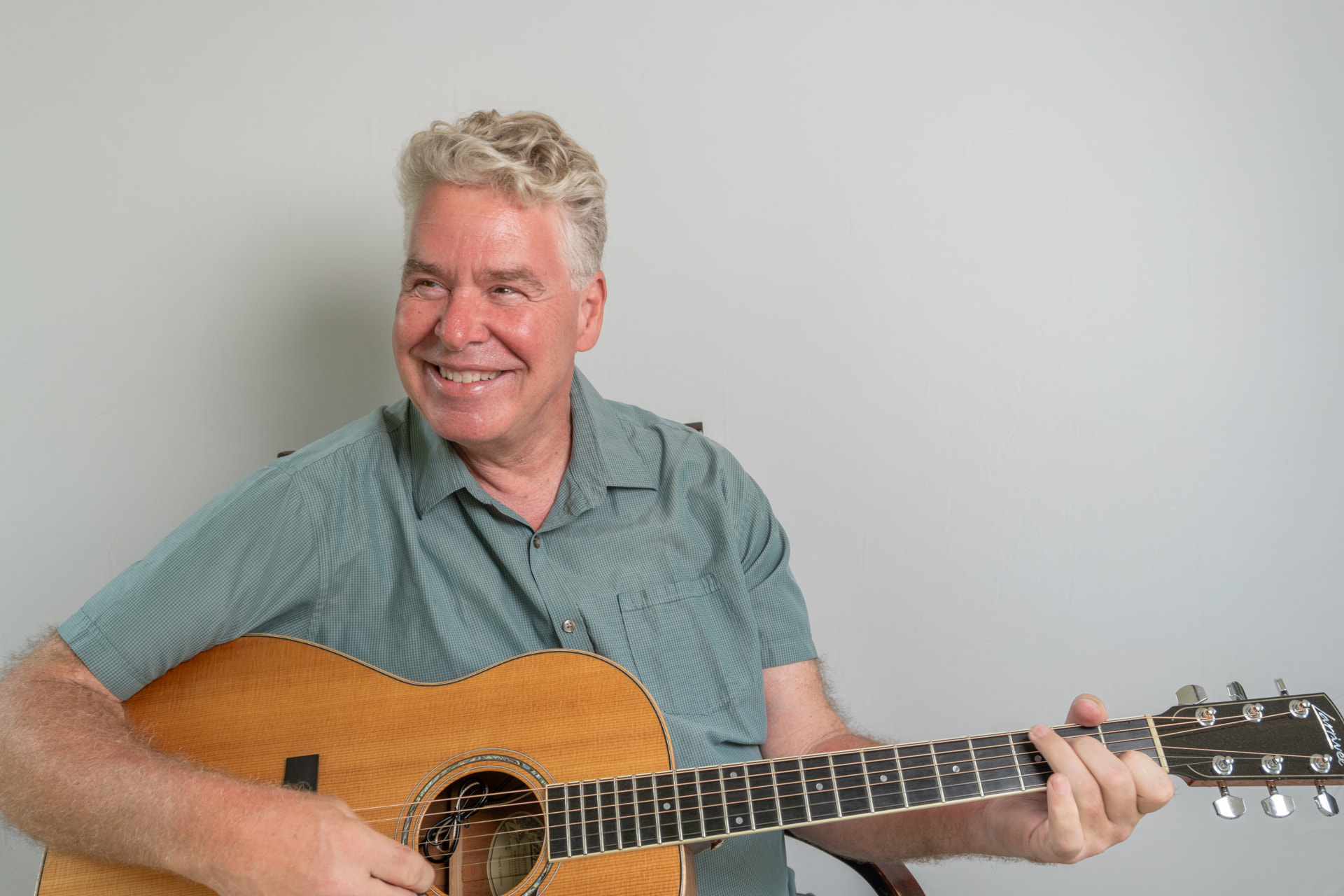 Ehlert P. Lassen smiling while playing acoustic guitar